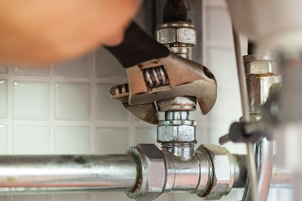 Closeup of wrench fixing pipes - Residential Plumbing